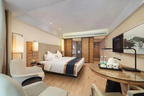 Una habitación de hotel con cama, escritorio, silla, televisor y un cuadro en la pared.