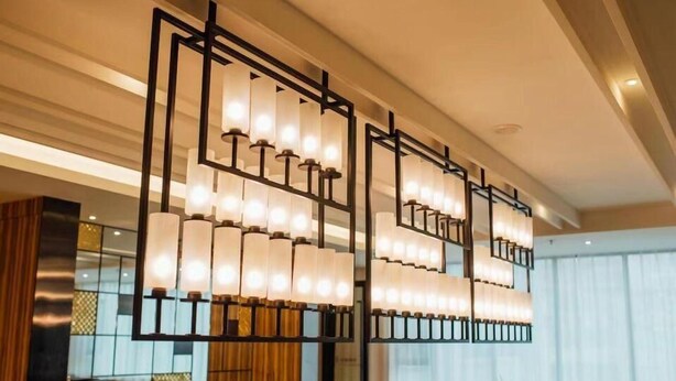 A modern hotel lobby with a large, geometric chandelier and a reception desk.