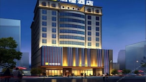 A modern hotel with a curved facade, multiple floors, and a prominent signage at the top.
