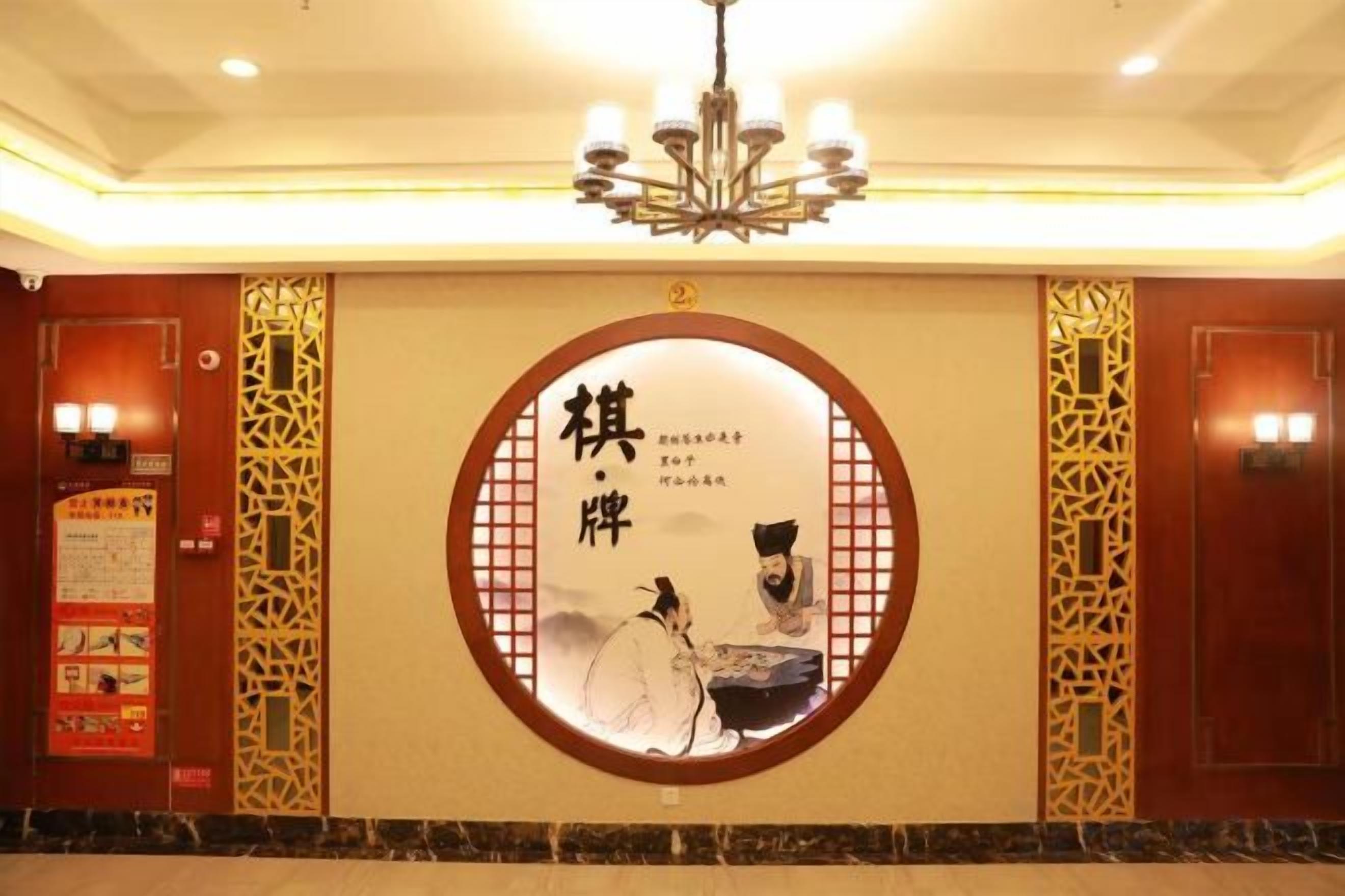 A hotel lobby with a traditional Chinese design, featuring a circular emblem with calligraphy and a chandelier.