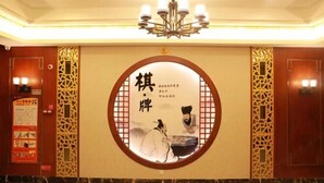 Un hall d’hôtel au décor de style chinois traditionnel, avec un emblème circulaire orné de calligraphie et un lustre.