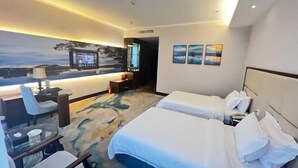 Une chambre d’hôtel avec deux lits, un bureau avec une chaise, une télévision et des œuvres d’art accrochées au mur.