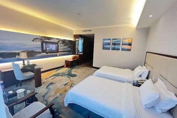 A hotel room with two beds, a desk with a chair, a TV, and artwork on the wall.