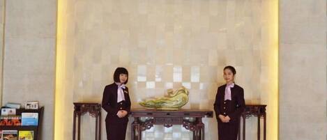 Two receptionists standing in front of a reception desk with a decorative vase.