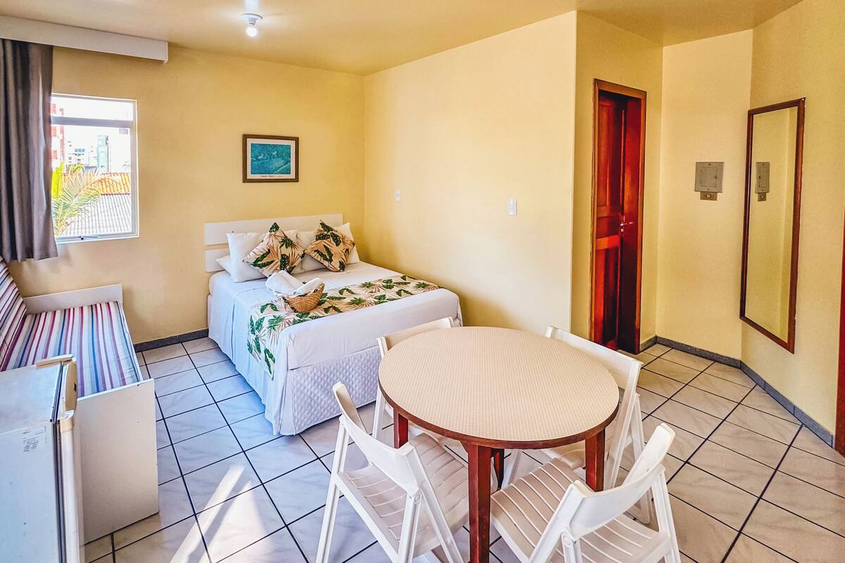 A compact room with a bed, a round table, and chairs.