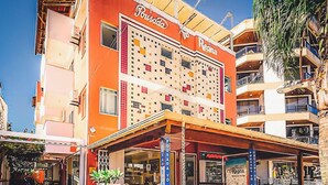 A hotel with a colorful facade, outdoor seating area, and a visible entrance. - Pousada Vó Regina (Florianópolis)