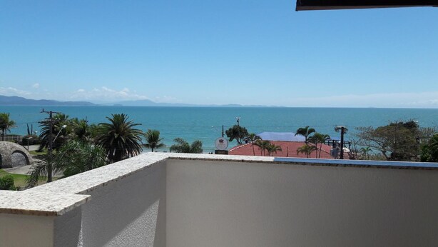 A balcony with a view of the sea and distant mountains. - Pousada Vó Regina (Florianópolis)