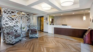Een receptiezone met een modern ontwerp, met een receptiebalie, een zithoek met gestreept fauteuils en een visgraatvloer.