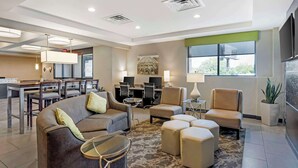 Een moderne hotel lobby met een gebogen bank, poefs, een zithoek en een groot raam met uitzicht.