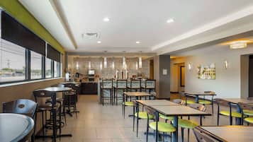 A modern restaurant with a long counter, multiple tables, and chairs.
