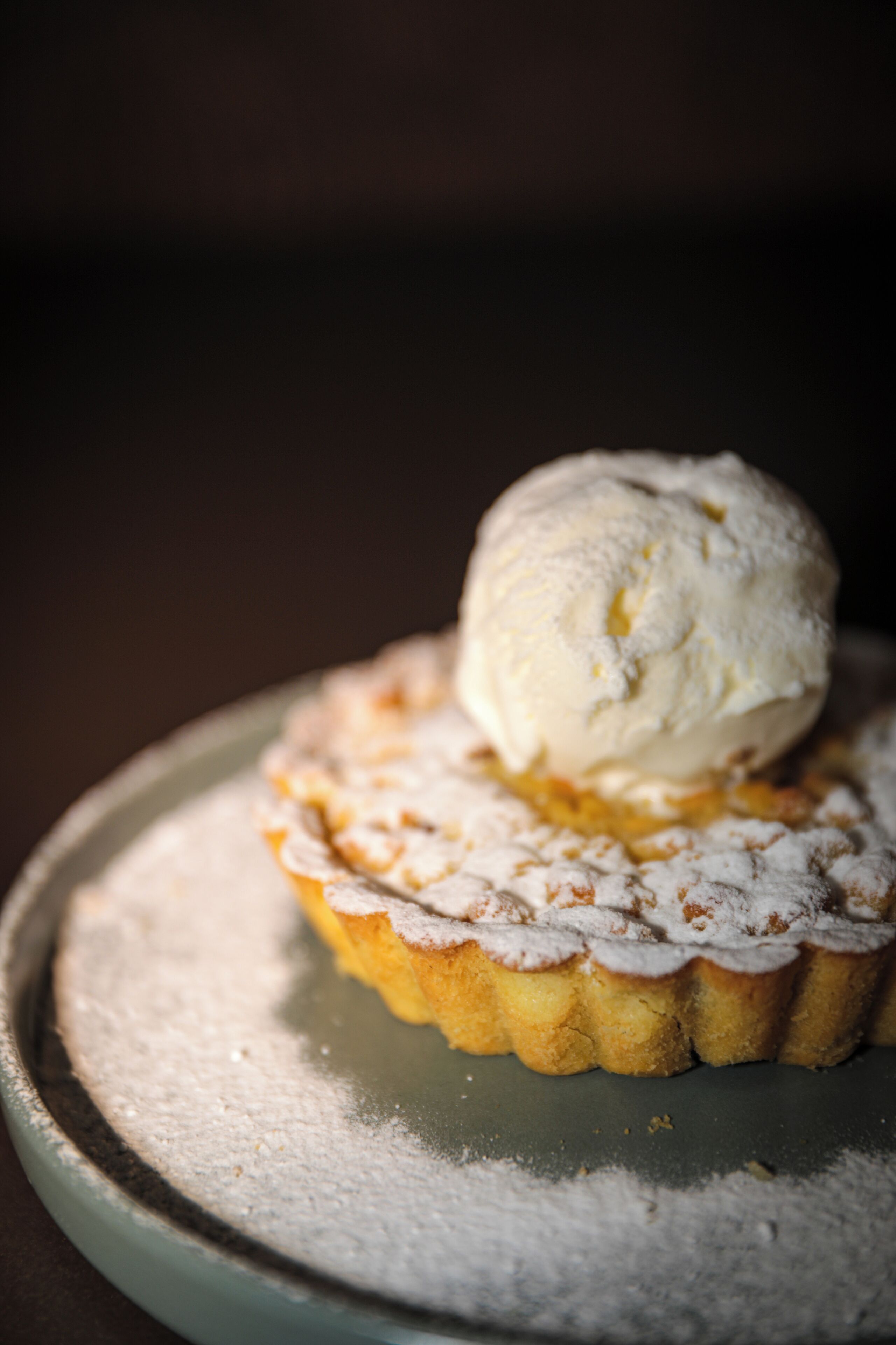 En dessert med en is kugle oven på et wienerbrød, drysset med flormelis.