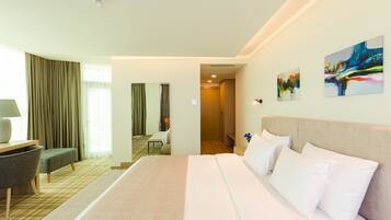 A hotel room with a large bed, a desk, a chair, and a bathroom visible through an open door.