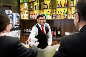 A bar setting with a bartender serving a customer. - Best Western Plus Royal Suites (Leipzig)