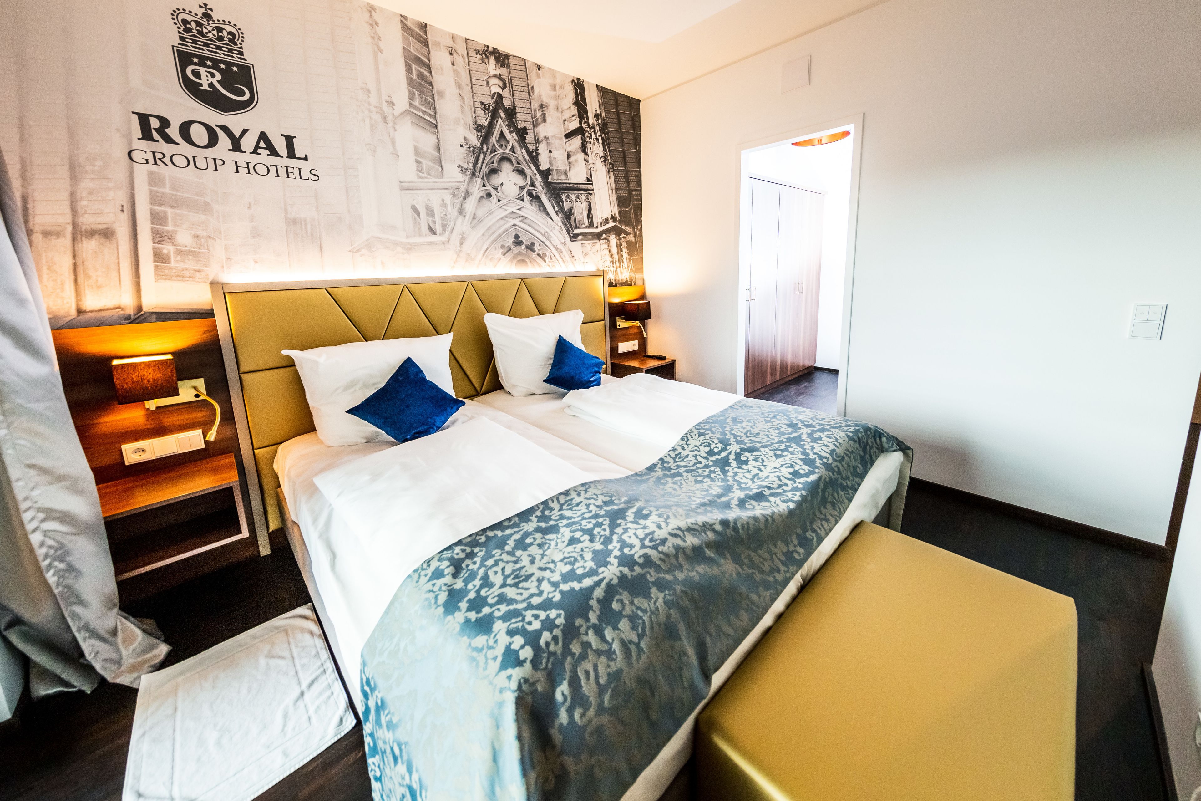A hotel room with a large bed, a bedside table, a nightstand, and a wall-mounted artwork.