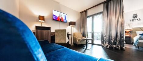 A hotel room with a large bed, a TV, a desk, and a chair.