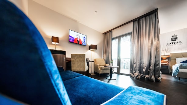 A hotel room with a large blue sofa, a television, a small table, and a bed.
