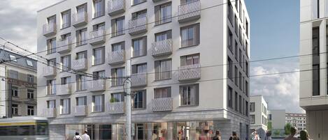 A modern multi-story building with balconies, large windows, and a ground-level commercial space.