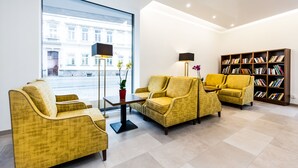 A modern living room with yellow armchairs, a coffee table, a floor lamp, and a bookshelf.