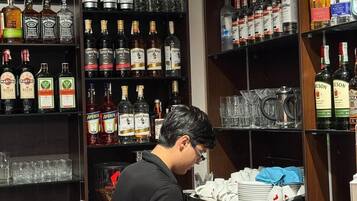 A bar area with shelves stocked with various liquor bottles, a coffee machine, and hanging glassware.