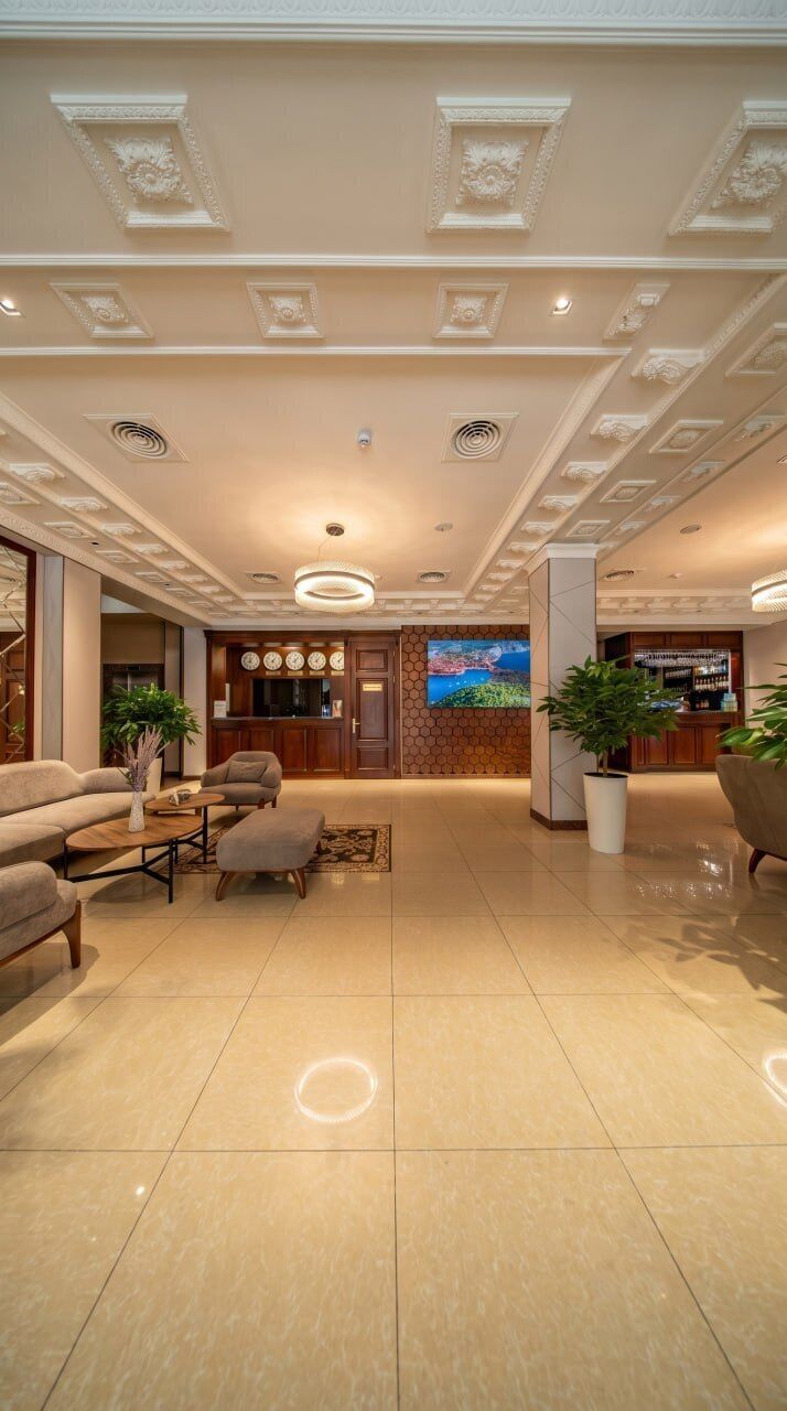 A spacious lobby with a reception desk, seating area, and a large screen.