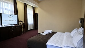 Hotellihuone, jossa on sänky, lipaston päällä oleva televisio ja kyltti, jossa on hotellin nimi.