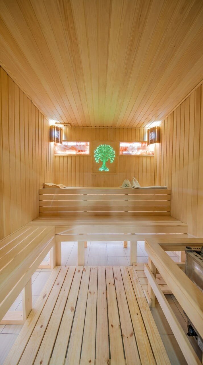 A wooden sauna with benches and a central tree-shaped light fixture.