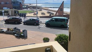 A coastal view from a balcony overlooking a beach, a parking area with cars, and a building with a restaurant named 'BAYA'. - Oceanfront apartment, opposite family beach. (Capbreton)