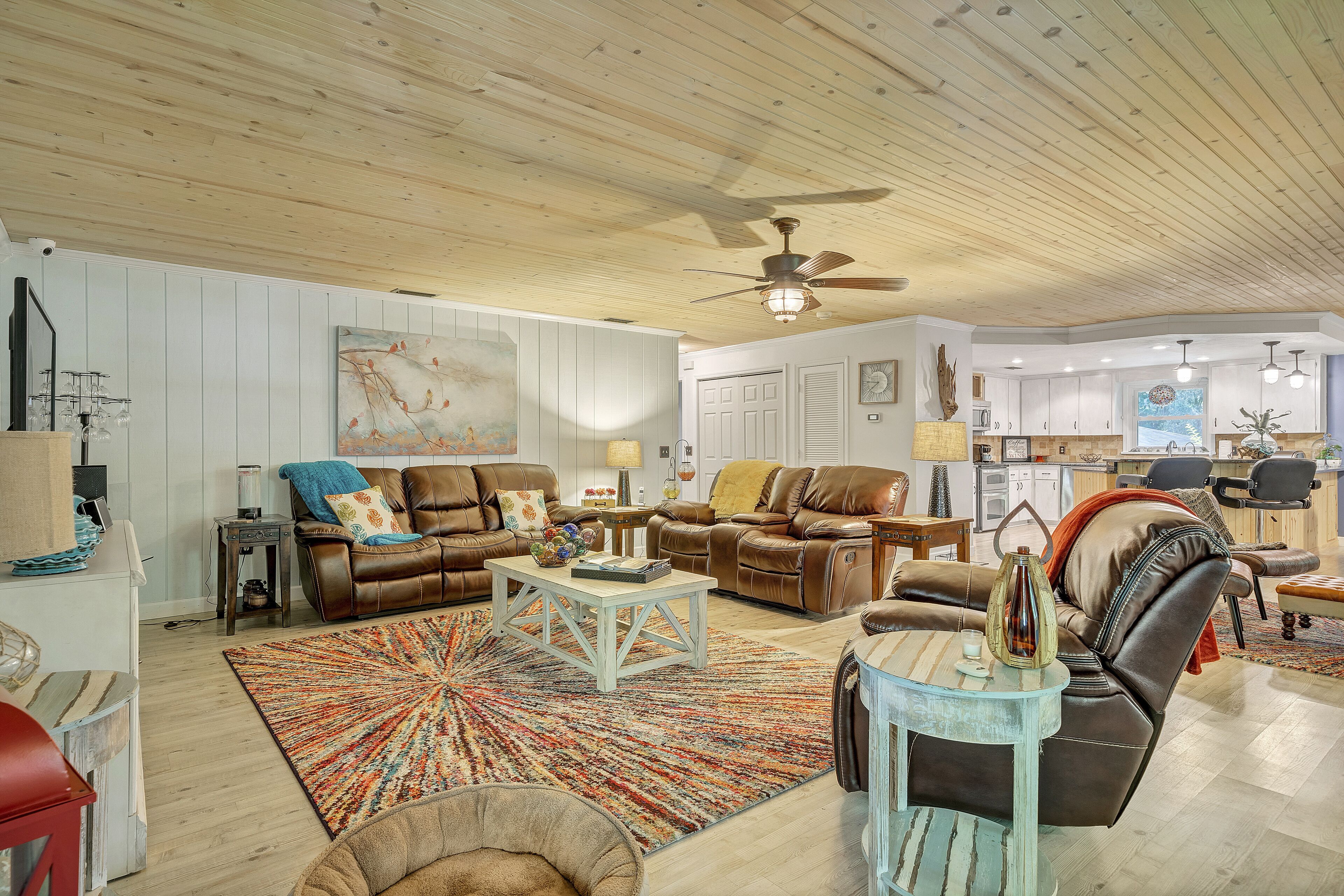 A spacious living room with leather sofas, a coffee table, and a large rug.
