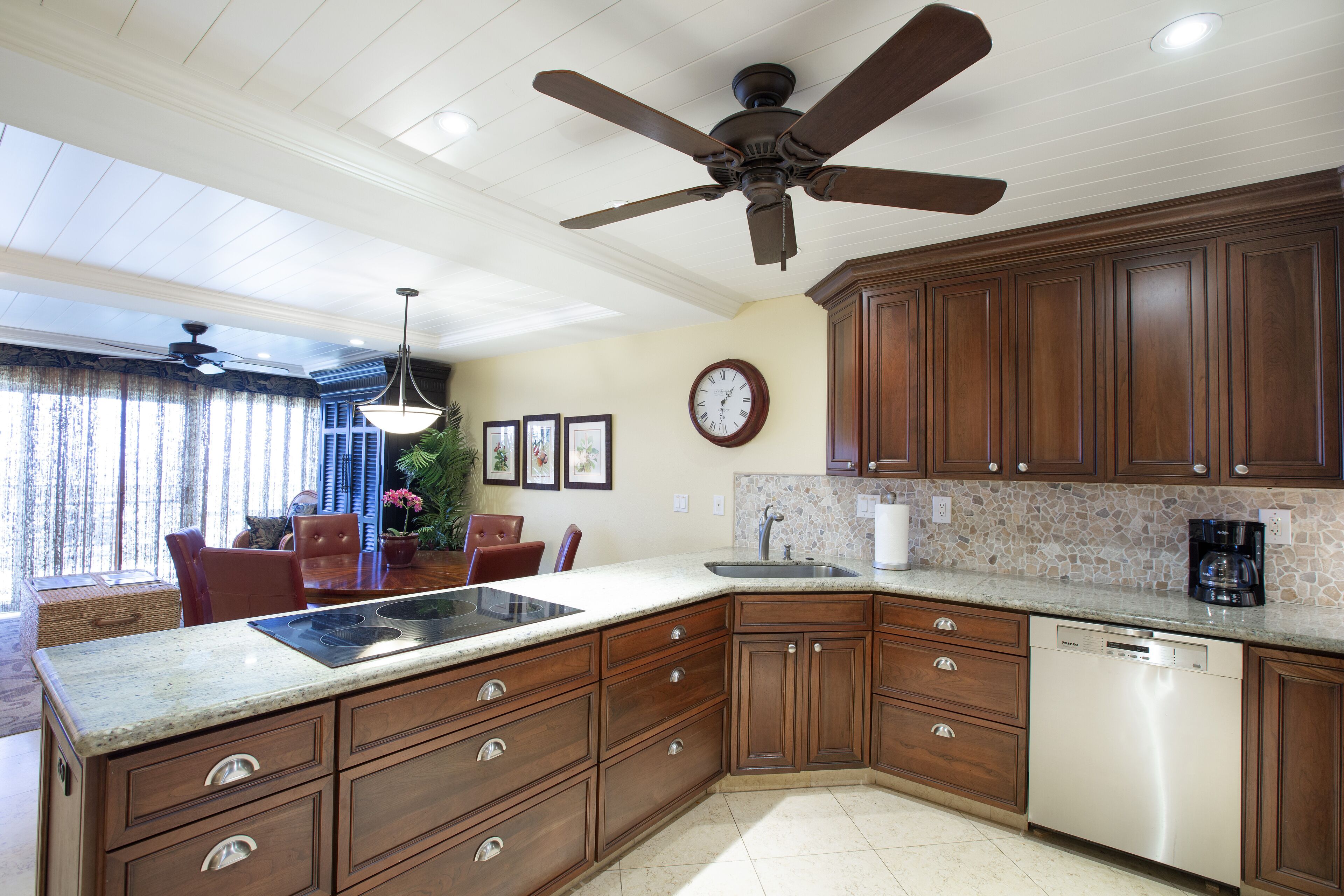 A kitchen with wooden cabinets, a dishwasher, and a ceiling fan.