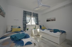 Ein modernes Schlafzimmer mit zwei Betten, einem Deckenventilator und einem Fenster mit Vorhängen.