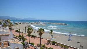 A coastal hotel with a beach view, palm trees, and a lifeguard tower. - Apartment close to the beach in La Duquesa (Manilva)