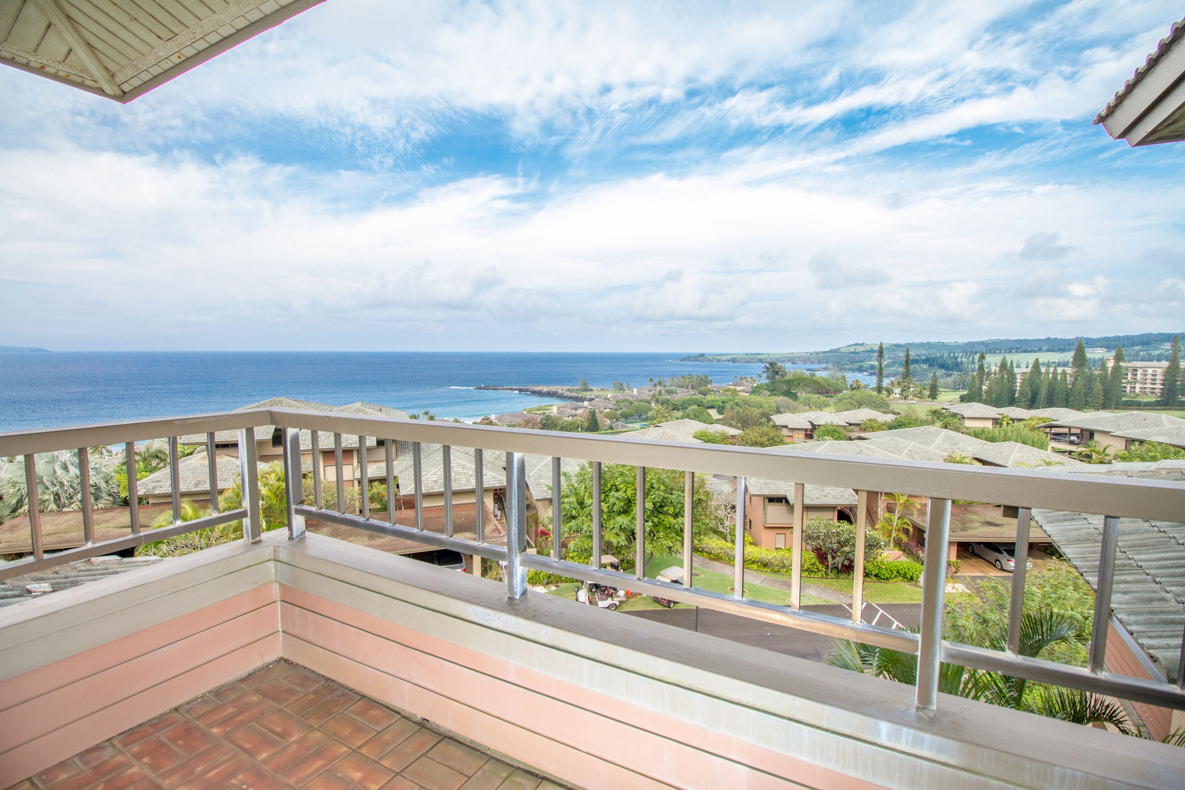 A balcony with a view of the ocean and residential buildings.
