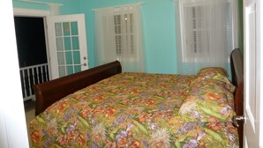 A bedroom with a floral bedspread, a wooden headboard, and a white door. - Home-styled cottage on Nevis with spectacular views of the Caribbean Sea  (Nevis)