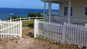 A coastal house with a white picket fence, a covered porch, and a view of the ocean. - Home-styled cottage on Nevis with spectacular views of the Caribbean Sea  (Nevis)