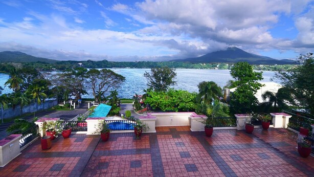 Terraza en la azotea con plantas en macetas, piscina y vistas a un lago y montañas.