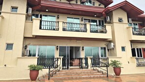 Un edificio de varios pisos con balcones, unidades de aire acondicionado y techo de tejas.