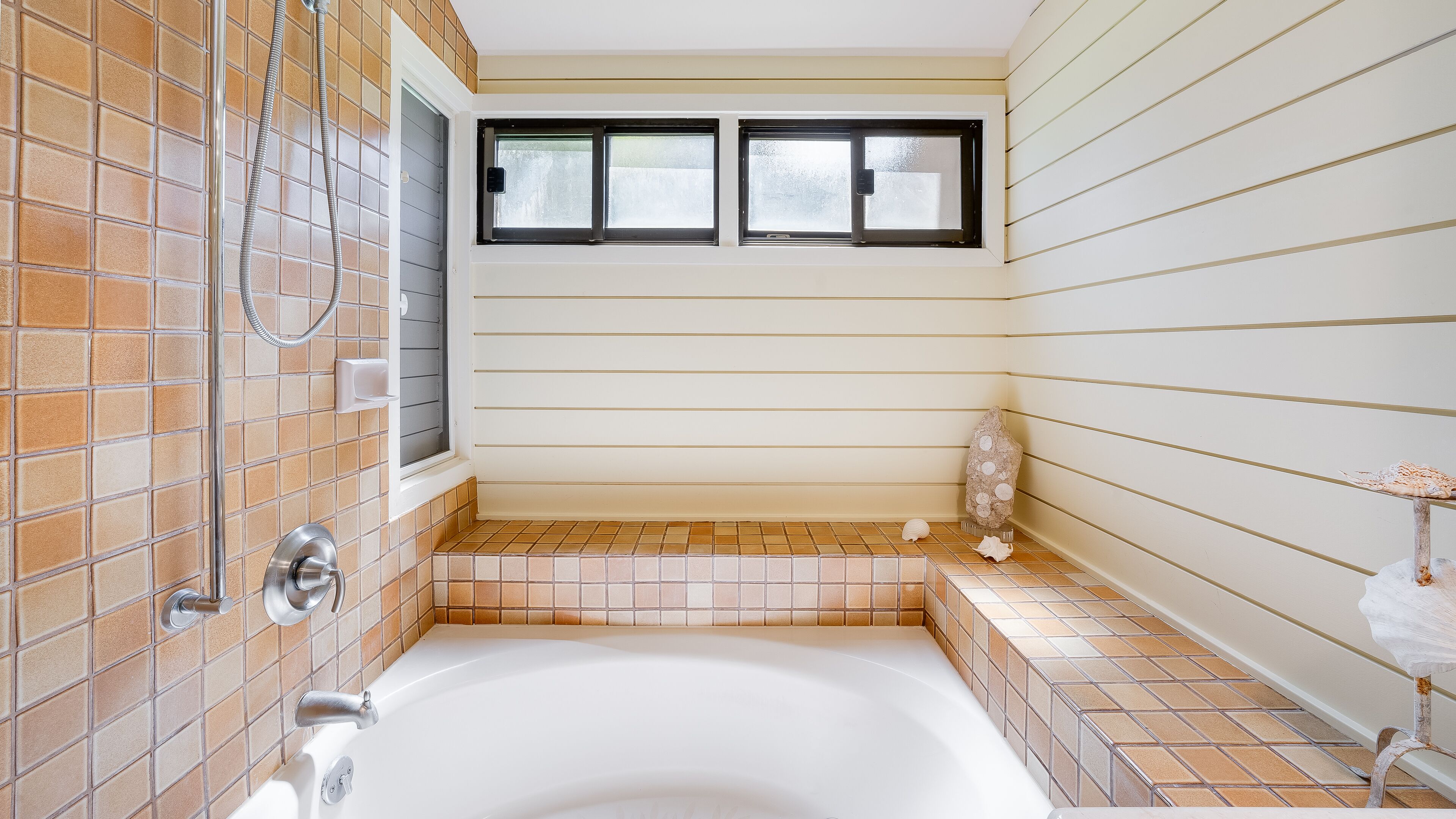 A bathroom with a bathtub, a shower, and a window.