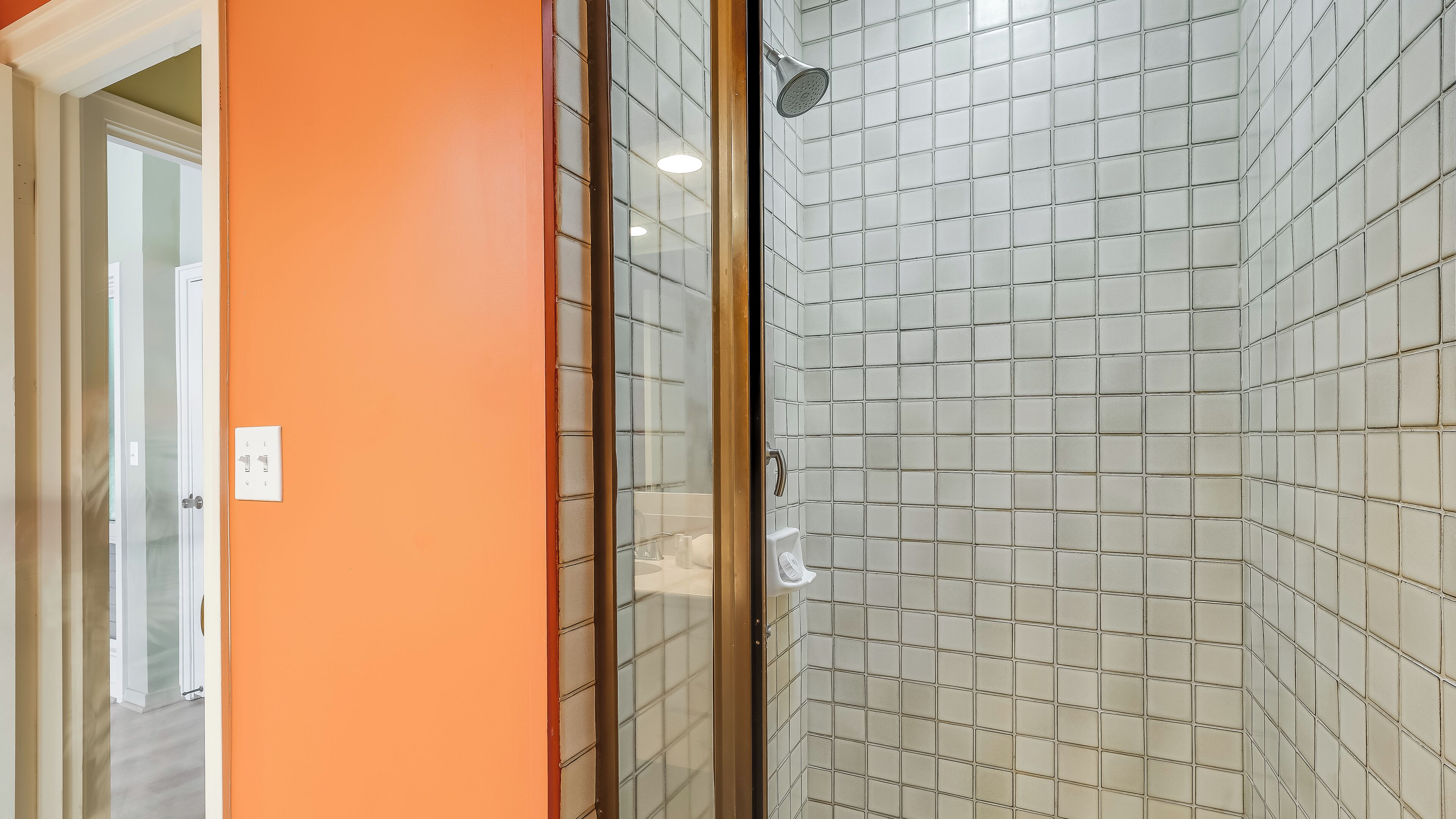Une salle de bain avec un espace douche, une porte en verre et un mur carrelé.