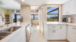 Enjoy a kitchen with a large window offering a view of the outdoors, dishwasher, and coffee maker.