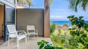 Enjoy the ocean view from this balcony with a table and two chairs.