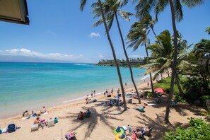 A beach with palm trees, people sunbathing, and beach chairs. - Napili Bay Steps from Ocean! Nb204 - Sullivan Properties (Lahaina)