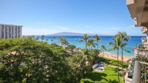 Un balcón de hotel con vista a una playa, palmeras y el océano.