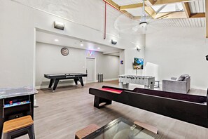 A billiards room with a pool table, foosball table, and a foosball table with a TV screen.