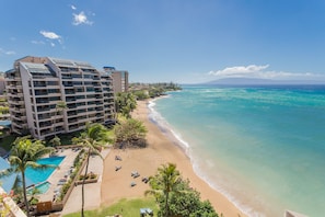 Un hôtel situé en bord de mer, doté d’une piscine, de chaises longues et de palmiers.
