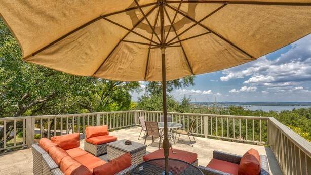 An outdoor patio with wicker furniture, a round table, and a large umbrella. - Relaxing townhouse with spectacular views of LBJ and the Hill Country. (Horseshoe Bay)
