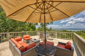 An outdoor patio with wicker furniture, a round table, and a large umbrella.