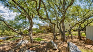 A house surrounded by large trees and rocks, with a clear sky. - Relaxing townhouse with spectacular views of LBJ and the Hill Country. (Horseshoe Bay)