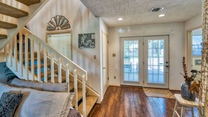 A spacious living area with a wooden staircase, a large window, and a door leading outside. - Relaxing townhouse with spectacular views of LBJ and the Hill Country. (Horseshoe Bay)