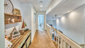A narrow hallway with a wooden bench, shelves with decorative items, and a staircase leading to an upper level. - Relaxing townhouse with spectacular views of LBJ and the Hill Country. (Horseshoe Bay)