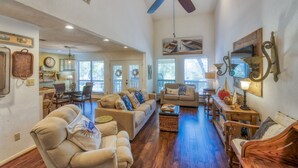A spacious living room with a ceiling fan, a dining area with a table and chairs, and a kitchen in the background. - Relaxing townhouse with spectacular views of LBJ and the Hill Country. (Horseshoe Bay)